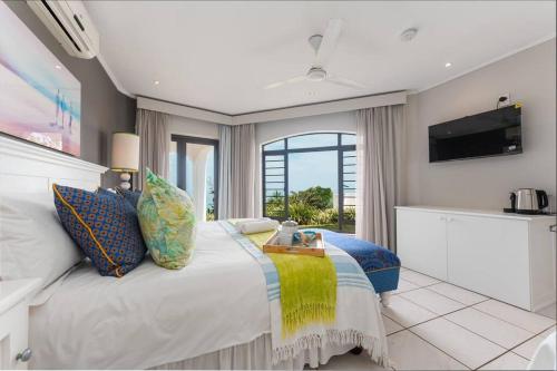 een slaapkamer met een groot bed en een tafel. bij Lalaria Ocean Villa Suite 3 in Ballito