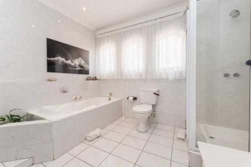 a white bathroom with a tub and a toilet at Lalaria Ocean Villa Suite 3 in Ballito