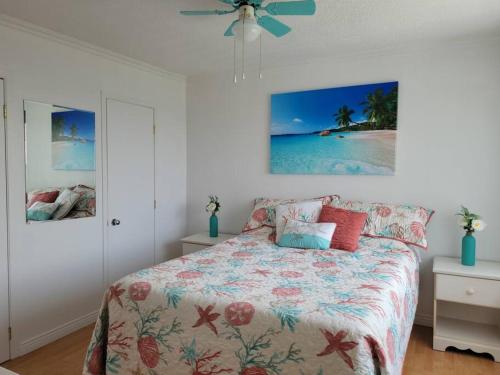 - une chambre avec un lit et une couette en fleurs dans l'établissement Maison Miramar à 5 min de la Baie, à Sainte-Luce-sur-Mer