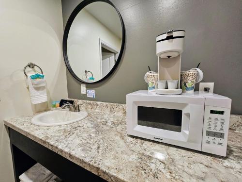 a kitchen counter with a microwave and a sink at The Honey Bee Motel in Dunlap