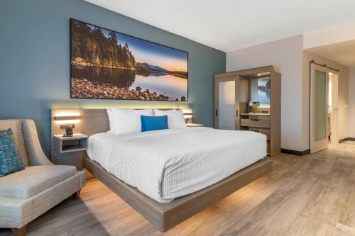 a bedroom with a large bed and a chair at Cambria Hotel Lake Placid - Lakeside Resort in Lake Placid