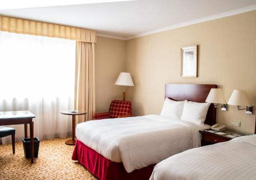 a hotel room with two beds and a desk at Paris Marriott Charles de Gaulle Airport Hotel in Roissy-en-France