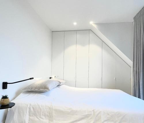a white bedroom with a bed with a white headboard at MOLO roof - stylish penthouse with marina view Blankenberge within walking distance from the sea - 15 km from Bruges in Blankenberge