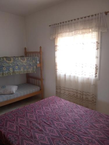 a bedroom with a bed and a window at Apartamento família perto do mar in Tramandaí