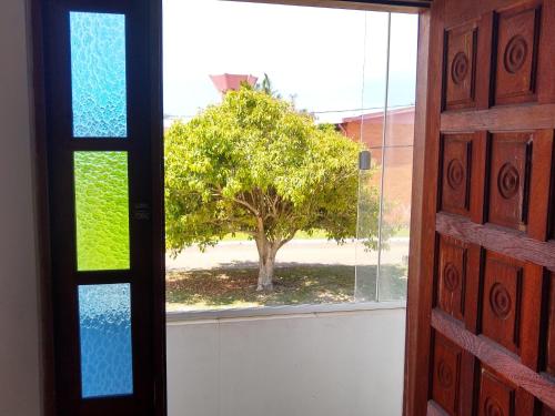 eine offene Tür mit Blick auf einen Baum in der Unterkunft Apartamento família perto do mar in Tramandaí