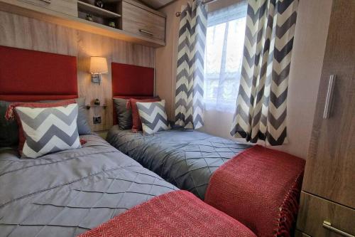 dwa łóżka w małym pokoju z czerwonym w obiekcie Contemporary home at Tarka Holiday Park Barnstaple w mieście Barnstaple
