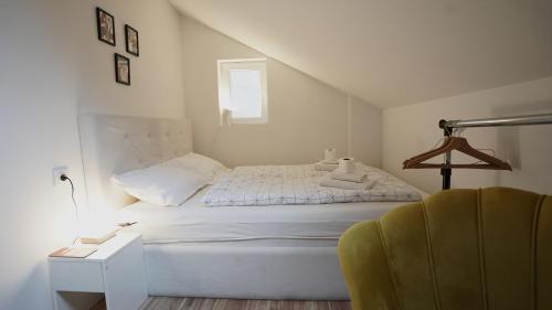 a white bedroom with a bed and a chair at Hideaway Rooms & Apartments Sarajevo in Sarajevo