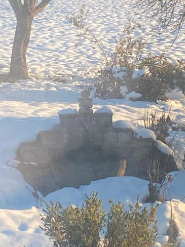 a statue of a person sitting on a wall in the snow at Annahof in Argenbühl