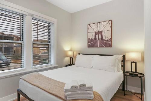 1 Schlafzimmer mit einem großen weißen Bett und 2 Fenstern in der Unterkunft Elegant 2BR Chicago Apartment - Montrose 1A in Chicago