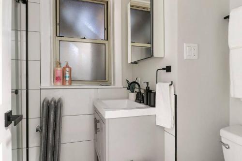 ein weißes Badezimmer mit einem Waschbecken und zwei Fenstern in der Unterkunft Elegant 2BR Chicago Apartment - Montrose 1A in Chicago