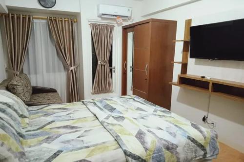 um quarto com uma cama e uma televisão de ecrã plano em Velito at Podomoro Golf View Apartment em Kampungsitu
