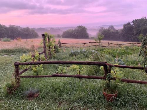 an old wooden fence in a field with grass at La Roulotte du Château de Framboise in Dumes