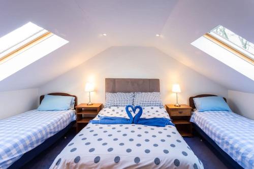 twee bedden in een zolderkamer met twee ramen bij PleasantHillScotland-Stunning 7BR GardenVilla Superior Area (Sleeps24) in Milngavie