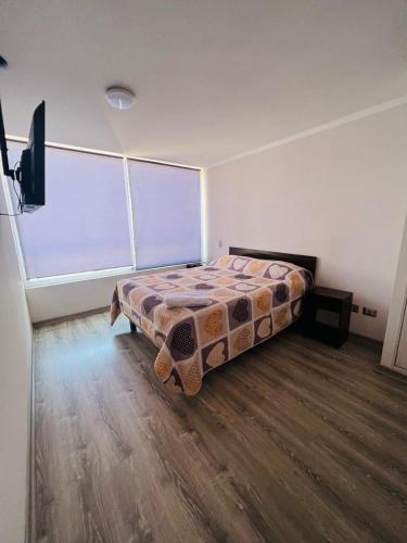 a bedroom with a bed and a large window at Apartamento vista al mar in Iquique