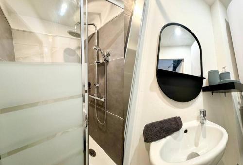 een badkamer met een wastafel, een douche en een spiegel bij AuKabest 3 * Proche ferry * Gare in Calais