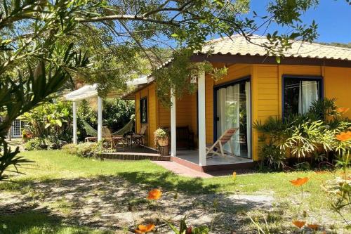 ein gelbes Haus mit einer Veranda und Stühlen im Hof in der Unterkunft São Francisco do Sul, SC, Praia do Forte. in São Francisco do Sul