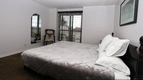 1 dormitorio con 1 cama con sábanas blancas y balcón en Cambridge 2 BR king gym Near Uni RUH City H en Saskatoon