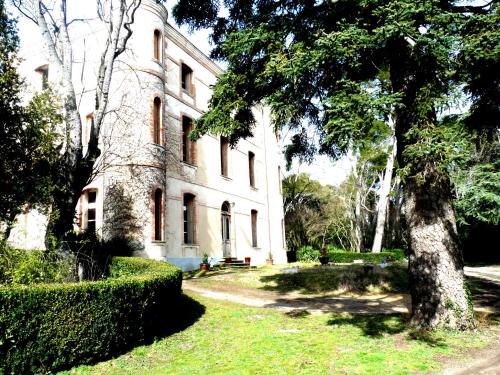an old white building with trees in front of it at Chateau la Bouriette in Moussoulens