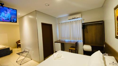 a hotel room with a bed and a tv on the wall at Hotel Nova Aliança in Chapadão do Sul