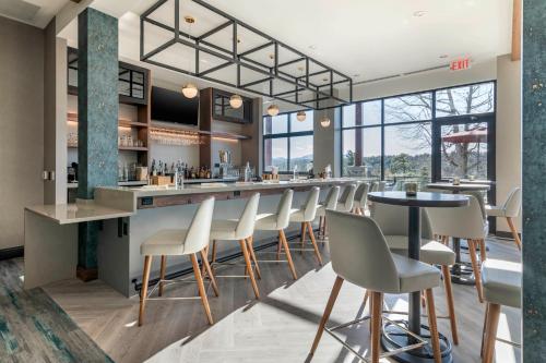 a bar in a restaurant with white chairs and tables at Cambria Hotel Lake Placid - Lakeside Resort in Lake Placid