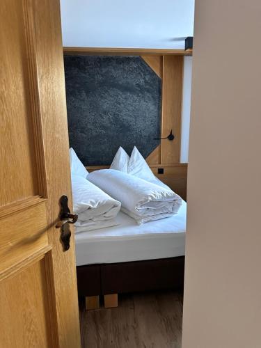 ein Bett mit weißer Bettwäsche und Kissen darauf in der Unterkunft Apartment Steinbock in Samnaun