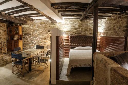 ein Schlafzimmer mit einem Bett und einem Tisch in einer Steinmauer in der Unterkunft BABhouse Casa do Avô Pedoucas - Coração do Douro in Nagoselo do Douro