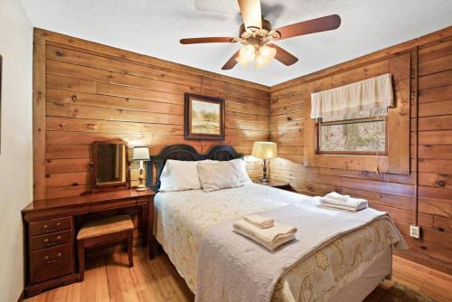 um quarto com uma cama e uma ventoinha de tecto em Picturesque Riverside Cabin with Fireplace and Porch em Blowing Rock