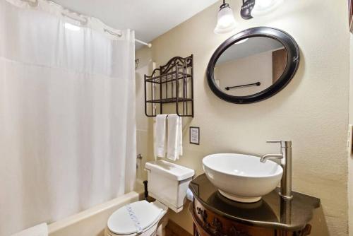 uma casa de banho com um lavatório, um espelho e um WC. em Picturesque Riverside Cabin with Fireplace and Porch em Blowing Rock
