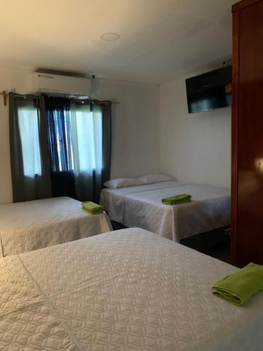 a room with three beds with green towels on them at Complejo Deportivo Wilson Palacios in El Perú