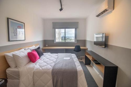 um quarto com uma cama, uma secretária e uma televisão em Metropolitan Sidney Smart Style em Goiânia