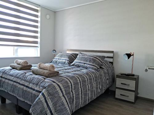een slaapkamer met een bed met kussens en een raam bij Departamento central con estacionamiento in Temuco