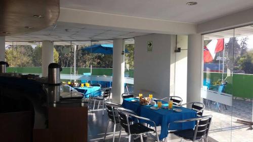 a dining room with blue tables and chairs and windows at HOTEL MURCIA AREQUIPA in Arequipa