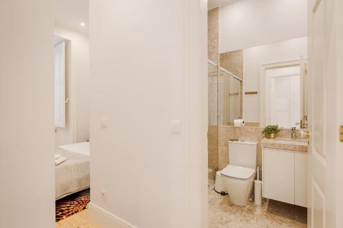 uma casa de banho com um WC, um lavatório e uma cama em Architectural Gem in Baixa em Lisboa
