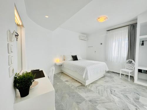 a white bedroom with a white bed and a table at Paradiso Boutique in Parikia
