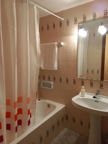 y baño con bañera, lavamanos y cortina de ducha. en Pis de l'Hereu. en Pobla de Segur