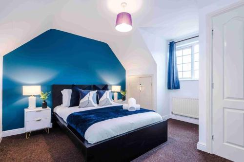a bedroom with a large bed with a blue wall at Inviting 3-Bedroom House in Warrington with Parking and Free Wifi by Amazing Spaces Relocations Ltd. in Warrington