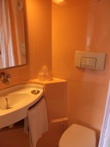 une salle de bain avec un lavabo, des toilettes et un miroir dans l'établissement Premiere Classe Angoulême La Couronne, à La Couronne