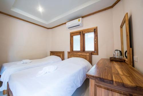 a bedroom with two beds and a wooden table at Thongphaphum River in Thong Pha Phum