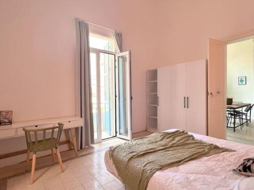 um quarto com uma cama, uma secretária e uma janela em Stone Wall 2BR Apartment em Beirute