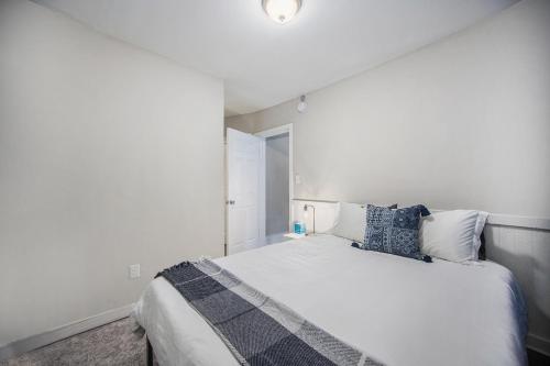 a white bedroom with a large bed with blue pillows at The Metropolitan Manor-new Corporate Apt Downtown in Grand Rapids
