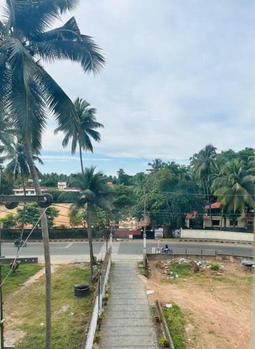 a path with palm trees on the side of a road at Soorya Madhavam Apartment Guruvayur - 200 m from temple walkable in Guruvāyūr