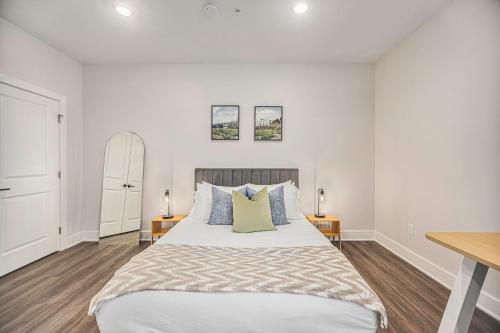 a white bedroom with a large bed with two tables at The Urban Oasis -brand New Corporate Apt Downtown in Grand Rapids