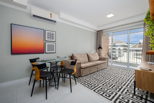 MOR - Apartamentos a 230m da Praia de Jurerê Floripa/SC في فلوريانوبوليس: غرفة معيشة مع أريكة وطاولة وكراسي
