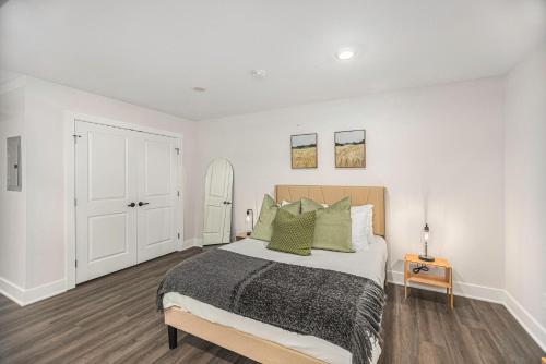 een witte slaapkamer met een bed met groene kussens bij Modern Manor - Brand New Corporate Apt Downtown in Grand Rapids