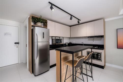 MOR - Apartamentos a 230m da Praia de Jurerê Floripa/SC في فلوريانوبوليس: مطبخ مع ثلاجة ستانلس ستيل و كرسيين للبار