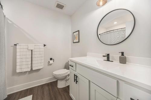 a white bathroom with a sink and a mirror at Modern Manor - Brand New Corporate Apt Downtown in Grand Rapids