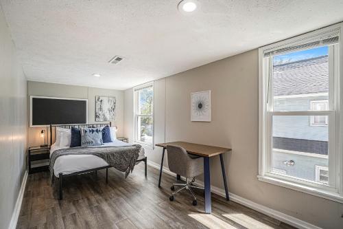 1 dormitorio con cama, escritorio y ventana en The Loft Life - Modern Corporate Housing, en Grand Rapids