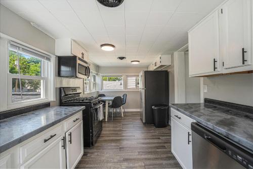 a kitchen with white cabinets and a black refrigerator at The Loft Life - Modern Corporate Housing in Grand Rapids