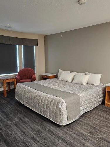 a hotel room with a large bed and a chair at Western Budget Motel #1 Leduc/Nisku in Leduc