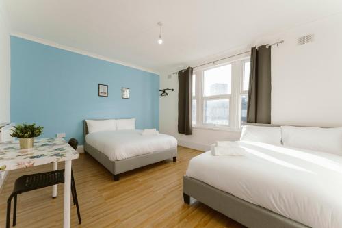 1 dormitorio con 2 camas y mesa con escritorio en Stratford Cosy Rooms - 37, en Londres